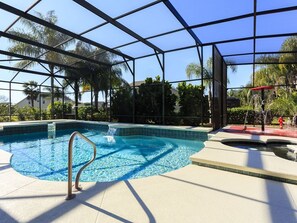 An indoor swimming pool with clear blue water, surrounded by a glass enclosure and palm trees. - Disney theme rooms,Splashpad, Movie Theater, Private Pool (Kissimmee)