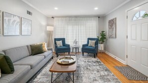A living room with a grey sofa, two blue armchairs, a coffee table, and a patterned rug. - Ranch Acres Expo-Heart of Tulsa (Tulsa)