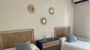 Une chambre avec deux lits simples, une table de chevet avec une lampe et des miroirs décoratifs sur les murs.