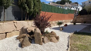Un jardin aménagé avec du gravier blanc, de gros rochers et un petit arbre.