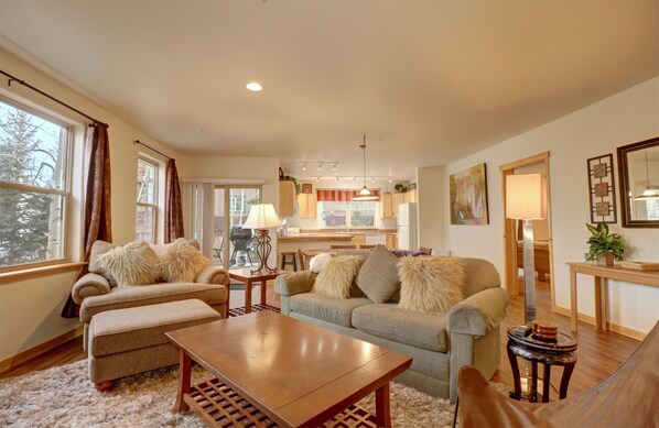A spacious living room with a sofa set, a coffee table, and a dining area with a lamp.