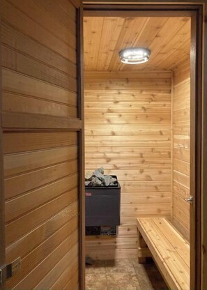 Relax in a serene sauna room with a bench and heater, featuring a storage area and ceiling light.