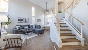 A spacious living room with a gray sectional sofa, a wooden coffee table, and a staircase with white railings. - Perfect Family Haven: 5BR,Heated Pool + Golf Green (Gilbert)