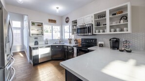 A modern kitchen with white cabinetry, stainless steel appliances, and a large island. - Perfect Family Haven: 5BR,Heated Pool + Golf Green (Gilbert)