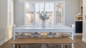 A dining area with a white table, four chairs, a bench, and a potted plant. - Perfect Family Haven: 5BR,Heated Pool + Golf Green (Gilbert)