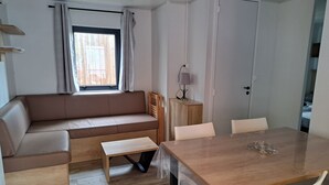 A modern, compact living space with a sofa, a dining table, and a small cabinet. - NEW AIR CONDITIONED MOBIL HOME - CAMPING 5* - FOR 6 PEOPLE with dishwasher (Lagorce)
