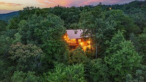 A cabin surrounded by dense forest, with a visible staircase leading to the entrance. - Smoky Mountain Cabin | Hot Tub + Pool Table (Sevierville)