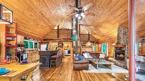 A spacious log cabin interior with a dining area, kitchen, living room, and fireplace. - Smoky Mountain Cabin | Hot Tub + Pool Table (Sevierville)