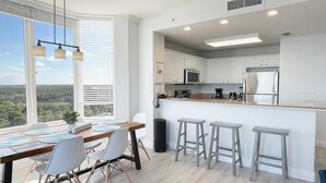 Una cocina moderna con armarios blancos, una isla central con taburetes y una zona de comedor con vistas.
