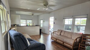 Een ruime woonkamer met een houten vloer, een bank, een stoel en een kleine tafel.