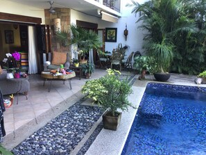 Ein Innenhof mit Pool, Topfpflanzen, einer Essecke und einer Treppe.