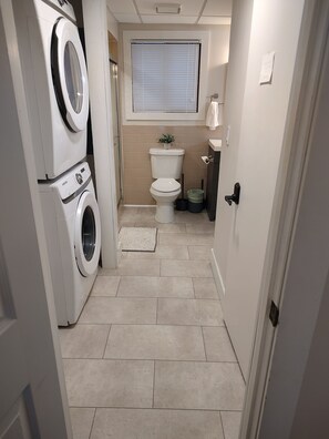 Ein kleiner Hauswirtschaftsraum mit Waschmaschine, Trockner, Toilette und einem kleinen Fenster.