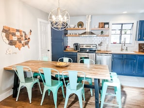 A kitchen with a wooden table, teal chairs, a chandelier, and a map of the USA on the wall. - quiet & clean lakefront, private dock & HOT TUB (Linn Creek)