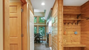 Un intérieur en bois avec un couloir menant à une salle à manger, des murs en bois et un sol carrelé.