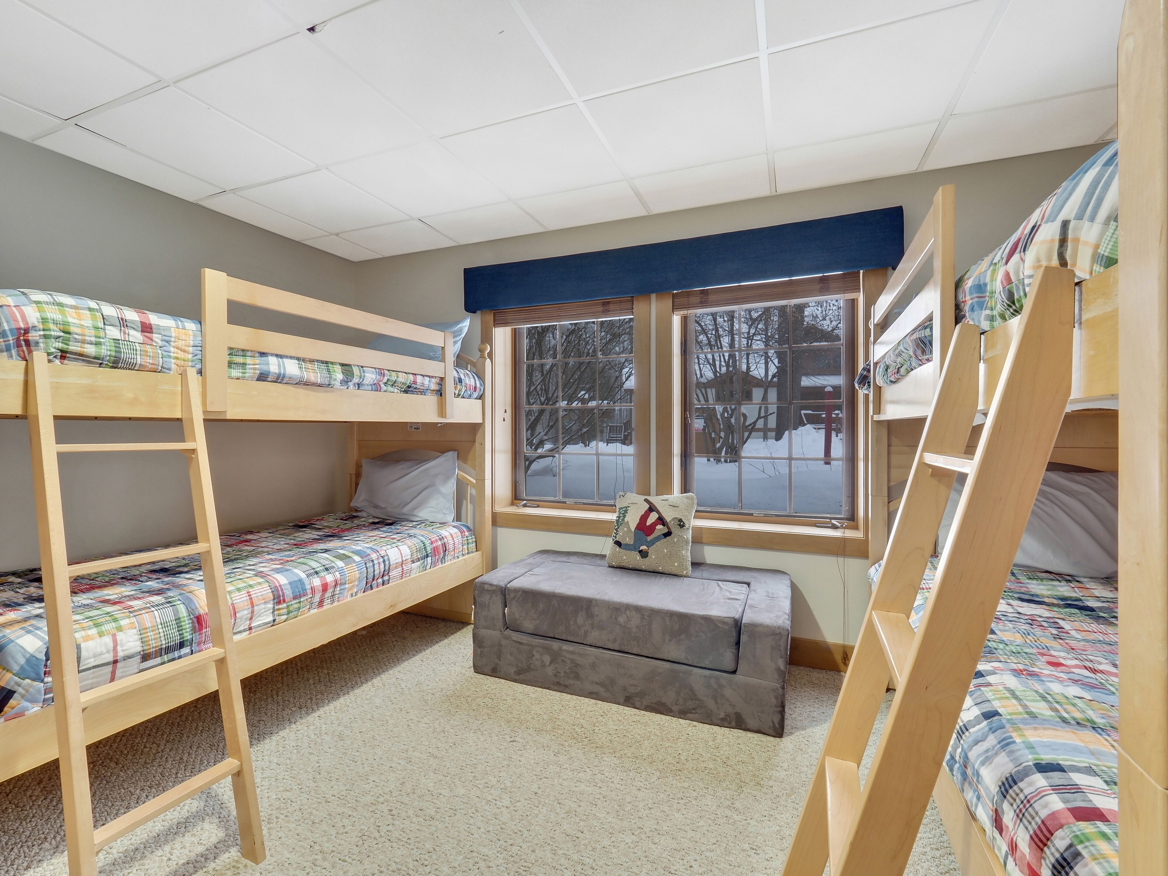 Un dormitorio con literas, una ventana que da a vistas exteriores y un pequeño banco.