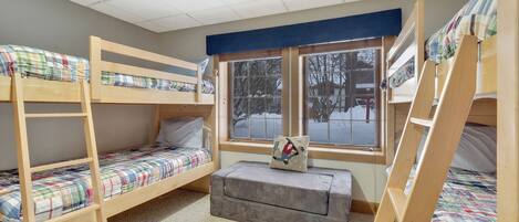Un dormitorio con literas, una ventana que da a vistas exteriores y un pequeño banco.