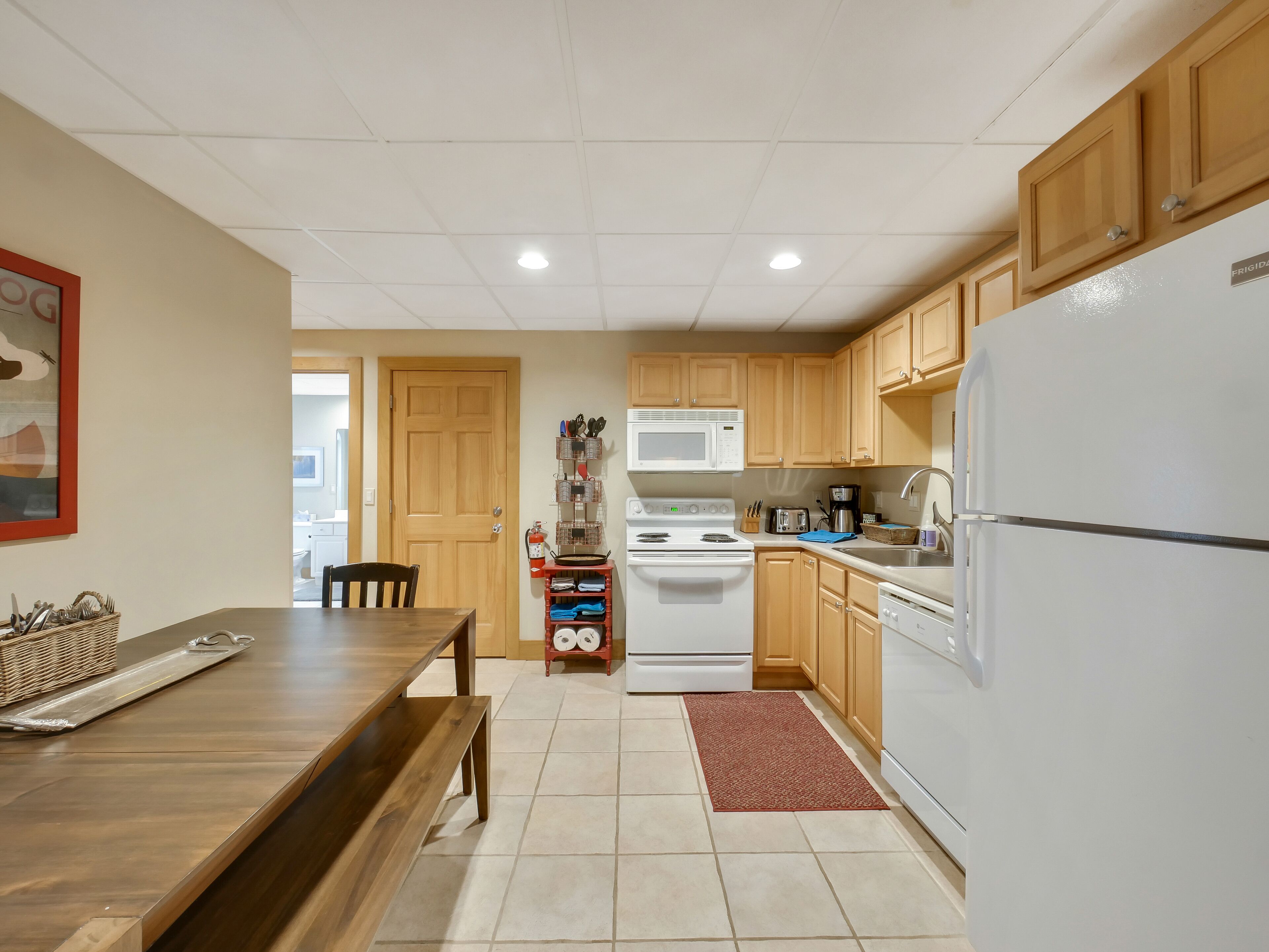 Une cuisine avec des meubles de rangement en bois, un réfrigérateur blanc, un four à micro-ondes, une cuisinière et un évier.
