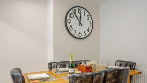 A dining area with a wooden table, black leather chairs, and a large wall clock.