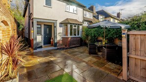 A residential property with a paved patio, a wooden fence, and a garden area.