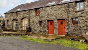A stone building with multiple doors and windows, a gravel driveway, and a small garden area. - Robin’s Nest - UK36208 (Capel Seion, near Aberystwyth)