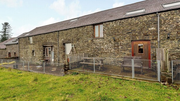 A stone building with a wooden door, a window, and a metal fence. - Robin’s Nest - UK36208 (Capel Seion, near Aberystwyth)