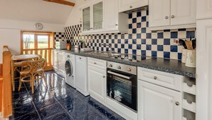 A kitchen with white cabinets, a checkered backsplash, a built-in oven, and a washing machine. - Robin’s Nest - UK36208 (Capel Seion, near Aberystwyth)