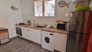 A compact kitchen with a washing machine, a microwave, and a sink. - Maisonette with terrace, 2 air-conditioned bedrooms  (Saint Anne)