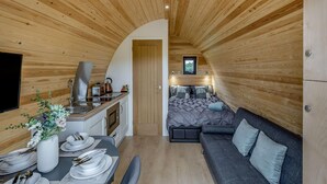 Un interior compacto revestido de madera con kitchenette, comedor y sofá.