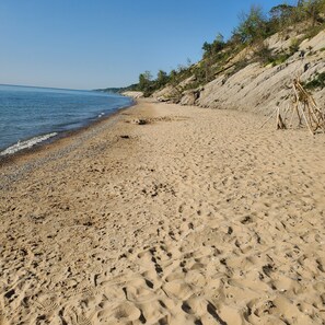 A sandy beach with footprints and a clear blue sky.