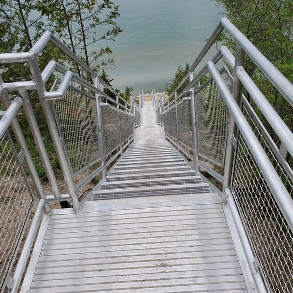 A metal staircase leading to a viewing platform with metal railings and a mesh barrier.