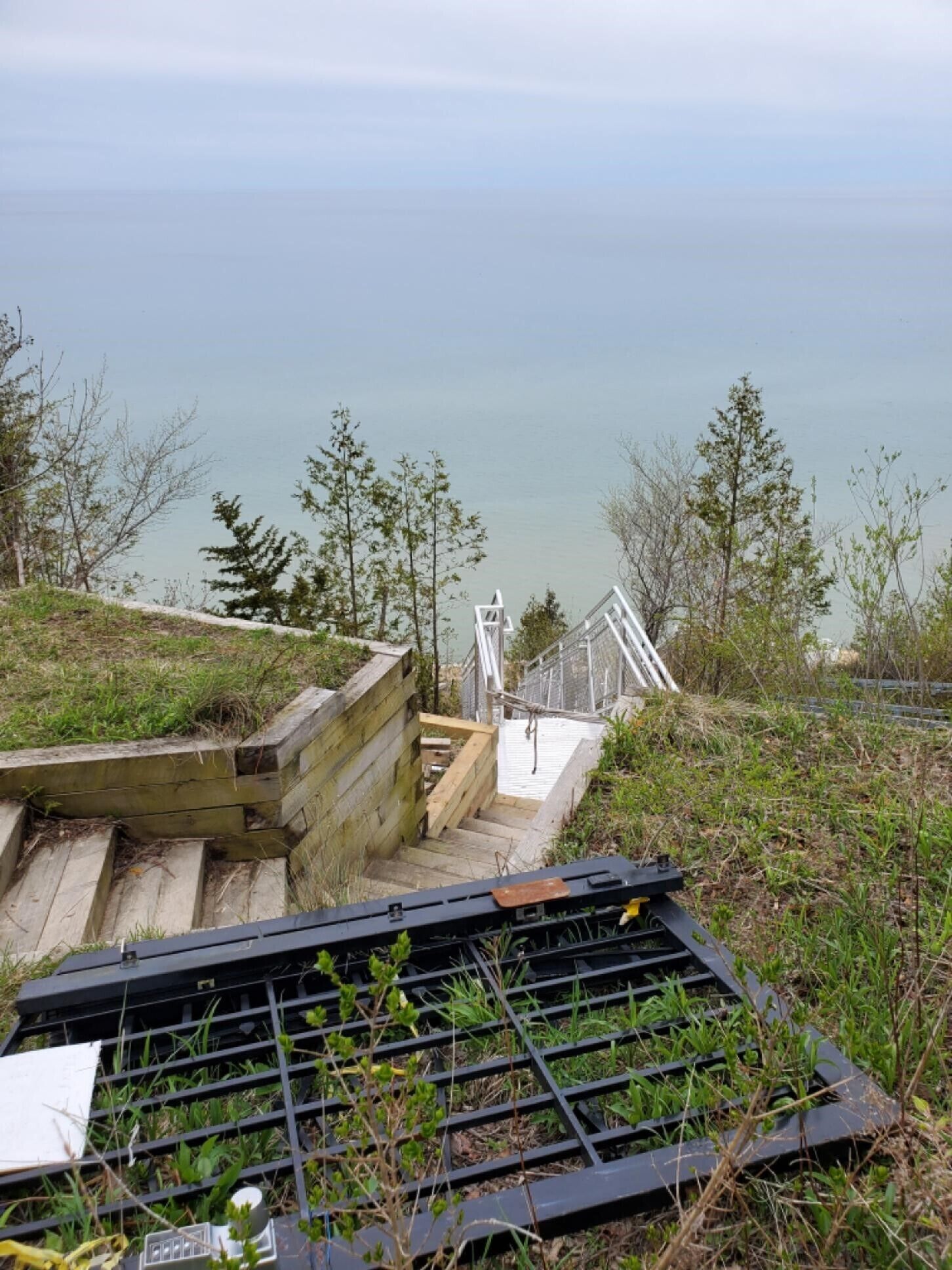 A wooden staircase leading to a metal railing overlooking a body of water.