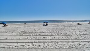 A beach with footprints leading to the water, a blue umbrella, and a few beach chairs. - Oceanfront Windsong Unit 207 | 1BR/1BA | Sleeps 5 | Queen, Bunks, Sofa Beds Setu (North Myrtle Beach)