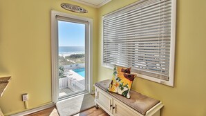 A room with a view of a pool and ocean, a door leading outside, and a window with blinds. - Oceanfront Windsong Unit 207 | 1BR/1BA | Sleeps 5 | Queen, Bunks, Sofa Beds Setu (North Myrtle Beach)