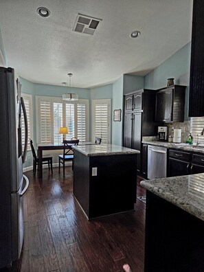 A kitchen with a central island, dark wood flooring, and a dining area with a table and chairs. - Las Vegas Pool Home Near Strip /Airport Holiday Dates Open & Discount Available
 (Las Vegas)