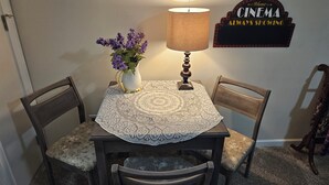 A dining table with a lace tablecloth, two chairs, a vase with purple flowers, and a lamp. - EXCLUSIVE LARGE 2 BEDROOM SUITE W/THEATER ROOM + KITCHEN  (Cleveland)