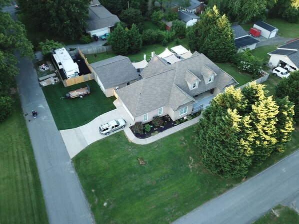 An aerial view of a residential area with houses, a driveway, and a green lawn.
