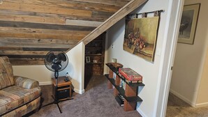 A cozy room with a wooden ceiling, a standing fan, a plaid sofa, and a bookshelf with board games. - EXCLUSIVE LARGE 2 BEDROOM SUITE W/THEATER ROOM + KITCHEN  (Cleveland)