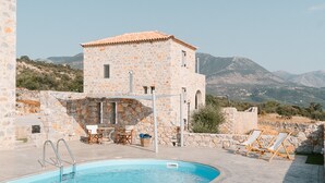 Un bâtiment en pierre doté d’une piscine et de chaises longues.