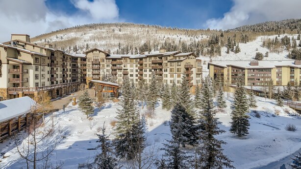 Hotel de diversos pisos amb un pati central envoltat d'arbres coberts de neu i un paisatge de muntanya al fons.