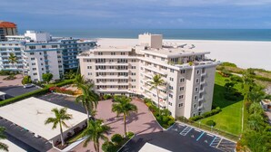 Ein mehrstöckiges Hotel mit Blick auf den Strand, einem Parkplatz und angelegten Grünflächen.