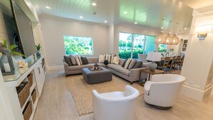 Ein geräumiges Wohnzimmer mit einer Sofagarnitur, zwei Sesseln, einem Couchtisch und einem Essbereich mit Tisch und Stühlen.