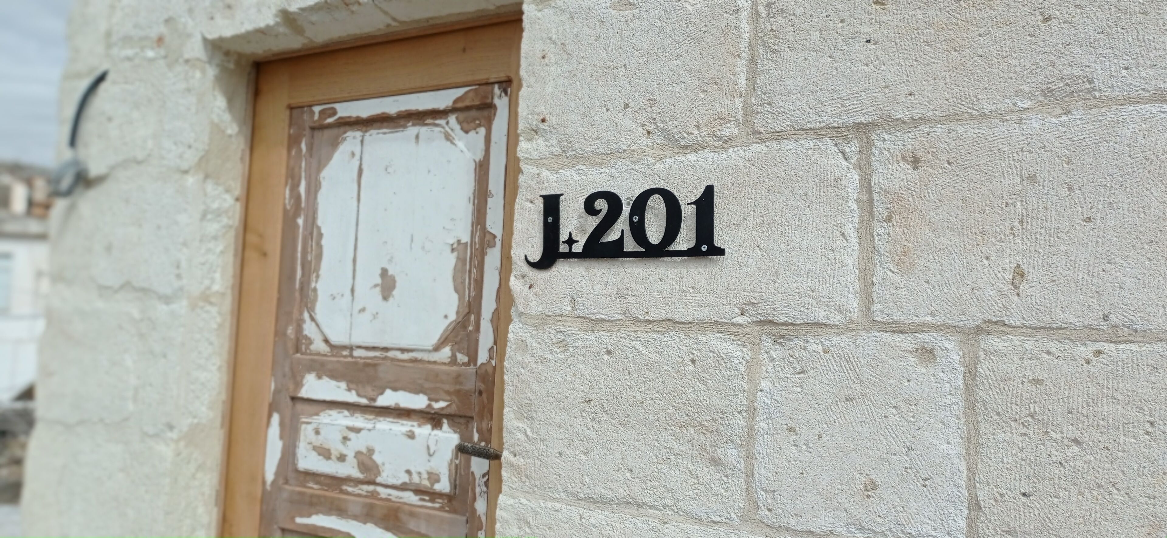 A house number plaque 'J201' on a textured wall.