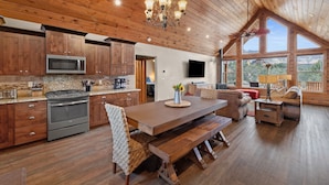 A spacious kitchen with wooden cabinets, a built-in microwave, and a large dining table with benches. - Skyfall Cabin | Private Hot tub | Zion NP (Orderville)