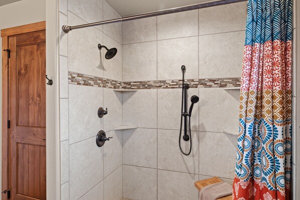 A shower area with a tiled wall, a wooden door, and a showerhead. - Skyfall Cabin | Private Hot tub | Zion NP (Orderville)