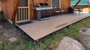 Une cabane en bois dotée d’un patio couvert, d’un barbecue et de meubles d’extérieur.