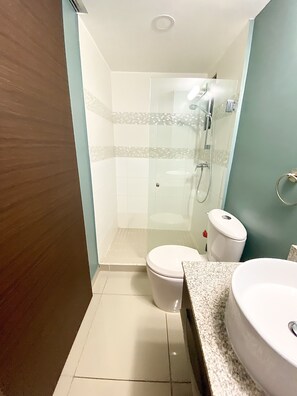 Un baño con ducha de vidrio, inodoro y lavamanos con encimera de granito.
