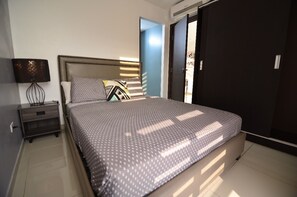 Un dormitorio con una cama, una mesita de noche, una lámpara y un armario.