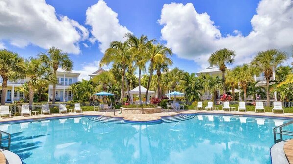 A swimming pool surrounded by palm trees and lounge chairs, with a clear blue sky. - Oceanside Anglers Reef Home+Beach, Pool and Kayaks (Islamorada)