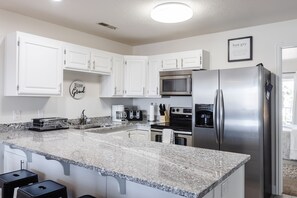 Enjoy cooking in this well-equipped kitchen with a large island, refrigerator, microwave, and oven.
