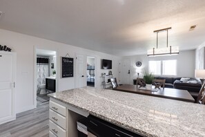 Enjoy meals in the kitchen and dining area, featuring a granite countertop, dishwasher, wooden table, and comfortable seating.